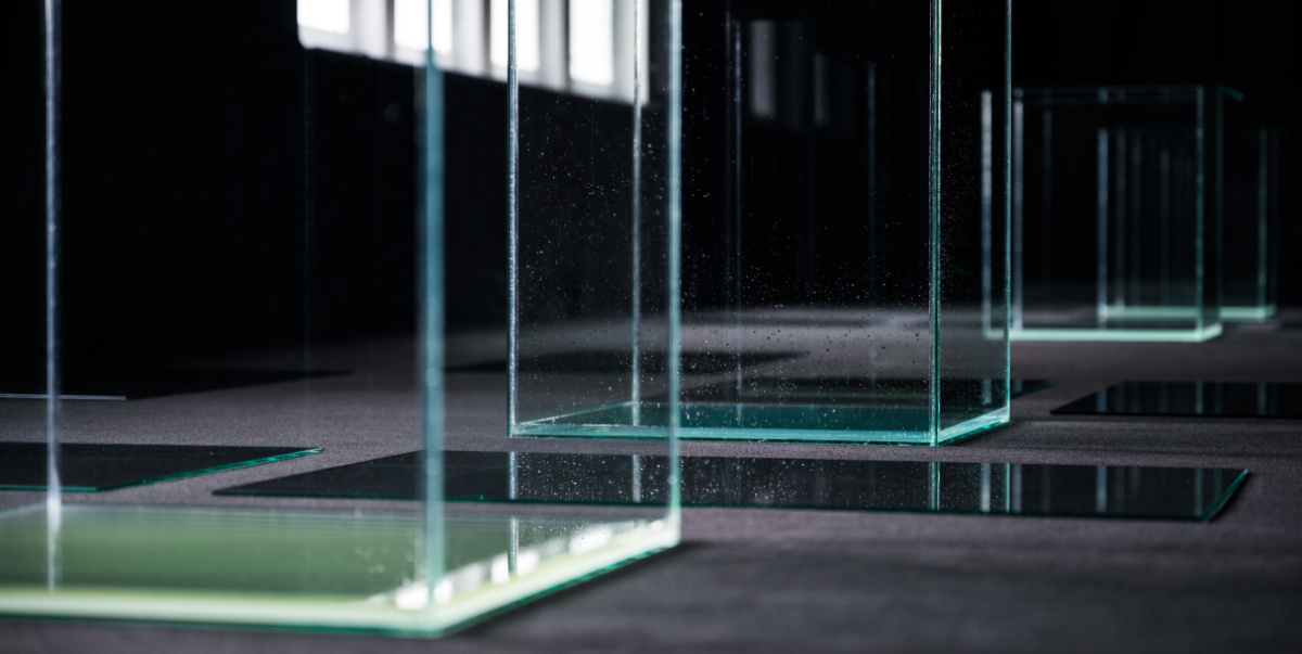 Matej Bosnić – πάσχειν (páskhein), 2021, Detail Ausstellung Stadtgalerie, Raum mit schwarzem Molton ausgelegt, große Glaskuben auf dem Boden mit Wasser befüllt. Das Wasser steht 2 CM hoch.