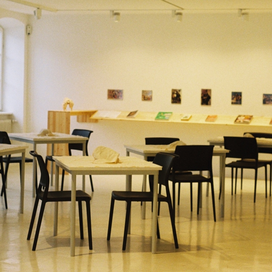 Tische und Stühle mit verhüllten Gegenständen stehen im Ausstellungsraum