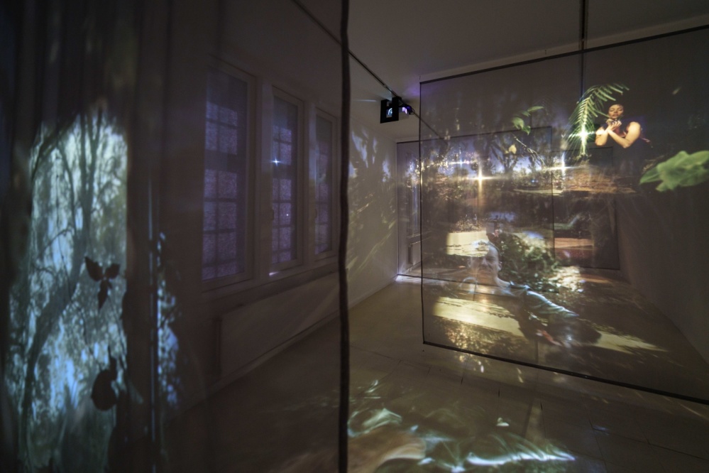 LOOPZONES Suzan Noesen Blick in den Ausstellungsraum, drei unterschiedliche Filmsequenzen laufen parallel auf transparenten Leinwänden