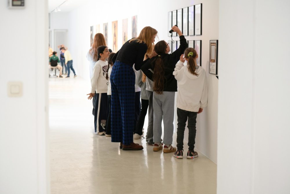 Kinder Eröffnung SUMM SUMM SUMM Stadtgalerie Eine Gruppe von Kindern und ein Erwachsener schauen sich mit einer Lampe eine Reihe von Bildern an